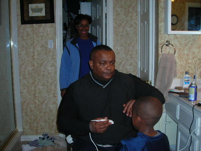 Michael giving his son a haircut while mom watches