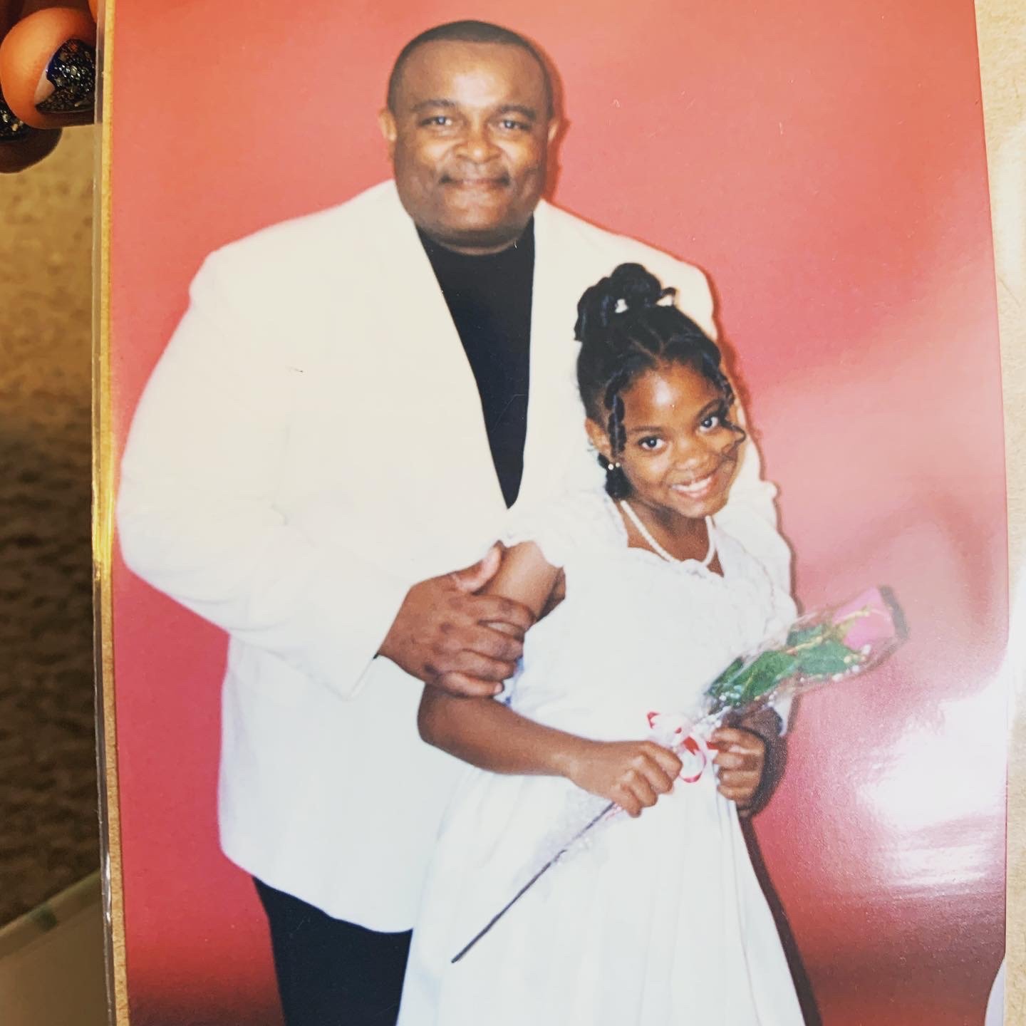Michael Gaiter in a white tuxedo jacket with young Gabriell holding a rose