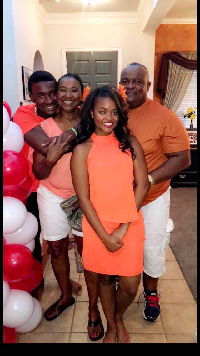 Family in coral outfits with red balloons